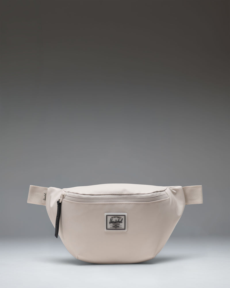 Herschel Supply Co. Pop Quiz Hip Pack in Moonbeam Tonal. A clean, minimalist beige fanny pack with a waterproof zipper and front pocket.