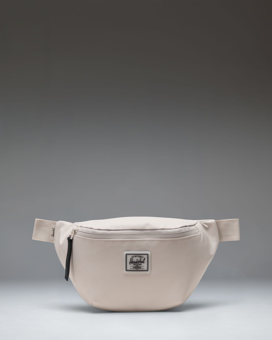 Herschel Supply Co. Pop Quiz Hip Pack in Moonbeam Tonal. A clean, minimalist beige fanny pack with a waterproof zipper and front pocket.