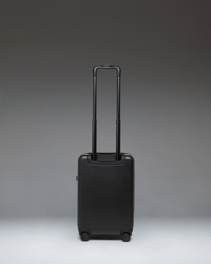 Black Herschel Heritage Hardshell Carry On Luggage in black, showcasing its durable hardshell exterior, wheels, and telescopic handle.