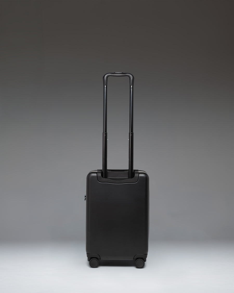 Black Herschel Heritage Hardshell Carry On Luggage in black, showcasing its durable hardshell exterior, wheels, and telescopic handle.