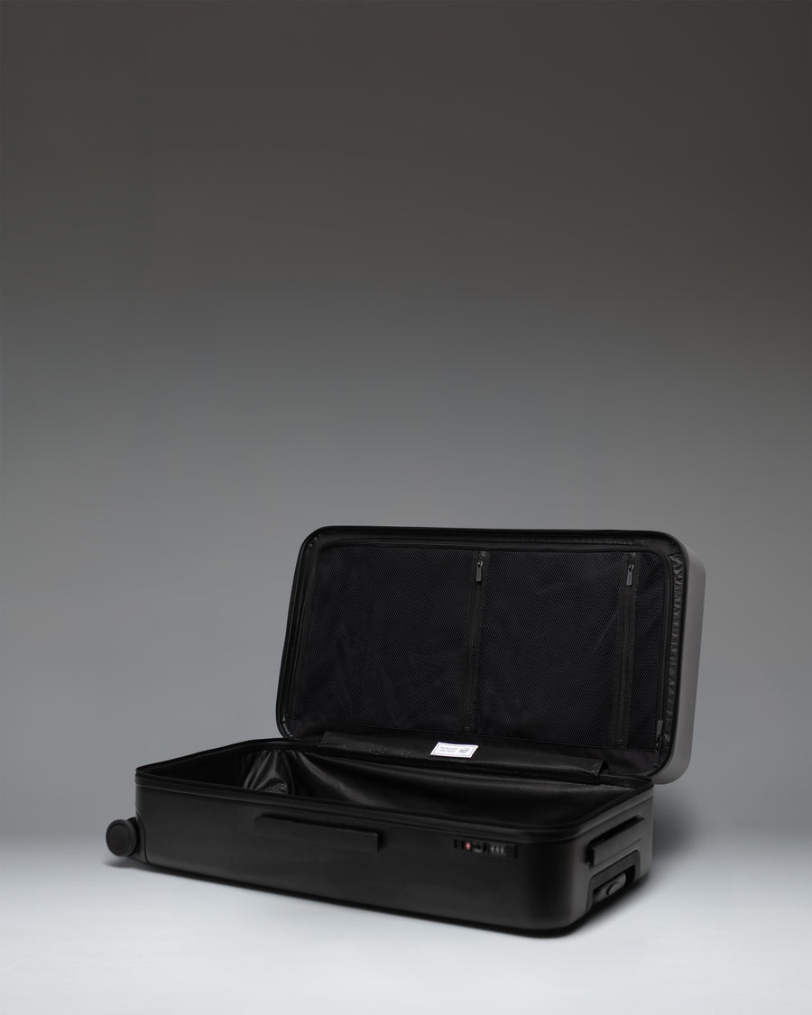 Black Herschel Heritage Hardshell Large Luggage on a white background, showing a side view profile.