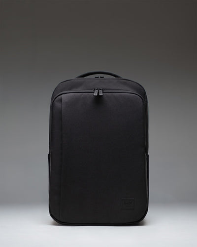 Black Herschel Supply Co. Kaslo Daypack Tech backpack viewed from the front, showcasing its clean design, dual top handles, and zippered pockets.