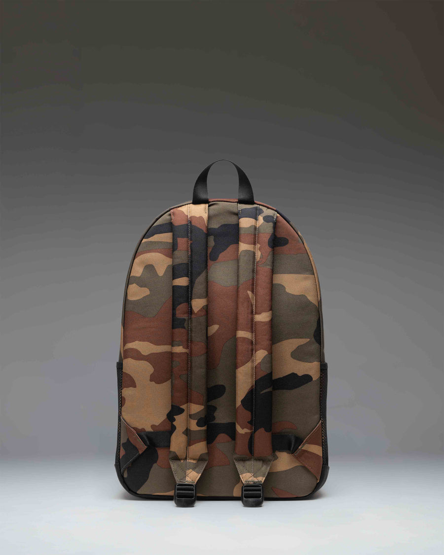 Herschel Supply Co. Kaine Backpack in Woodland Camo/Black featuring a front storage pocket, mesh water bottle pockets, and a haul handle.