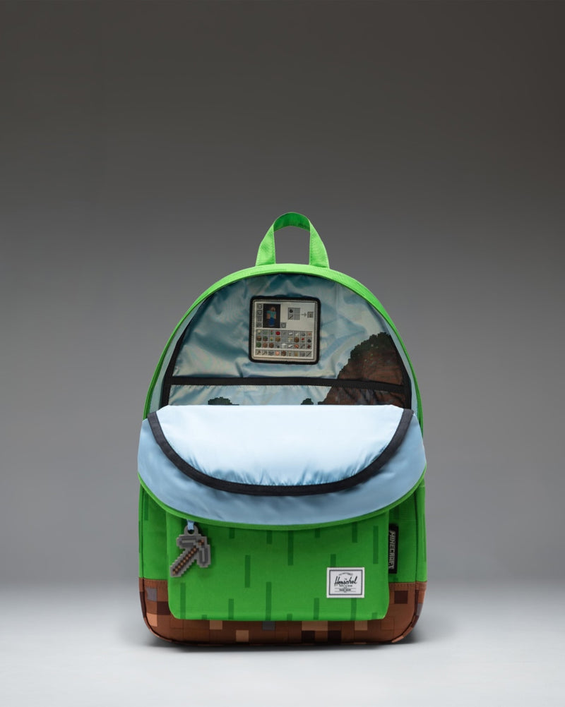 Minecraft Herschel Classic Backpack in The Overworld color scheme, showing the front pocket, zipper details, and pixelated green blocks.