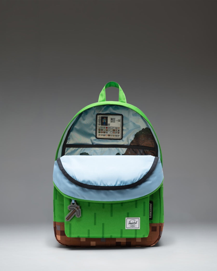 Minecraft Herschel Classic Backpack in The Overworld color scheme, showing the front pocket, zipper details, and pixelated green blocks.