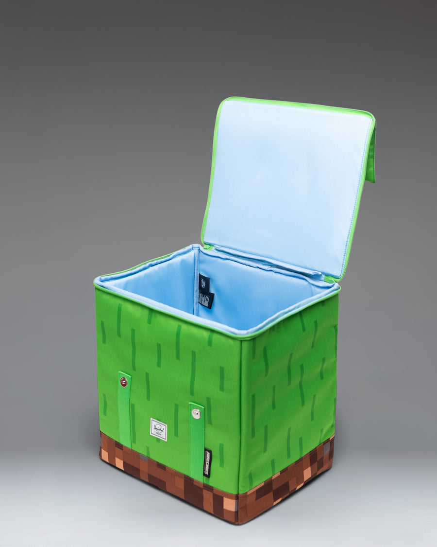 Herschel Supply Co. Minecraft Cube Backpack in Grass Block color showing the front view with classic pixelated green and brown design.