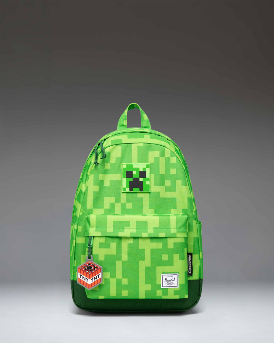 Herschel Supply Co. Minecraft Heritage Youth Backpack in pixelated green Creeper print, featuring a front storage pocket and diamond accent.