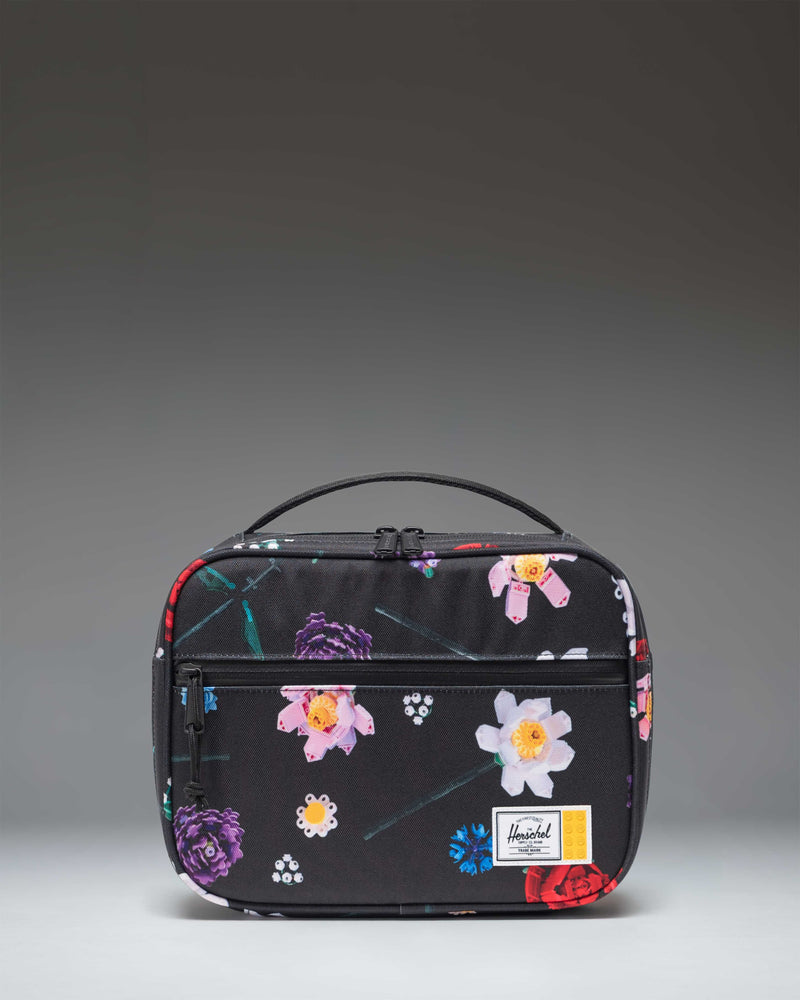 Herschel Supply Co. x LEGO Pop Quiz Lunch Box in the Falling Florals print, featuring a black background with colorful LEGO brick flower patterns.