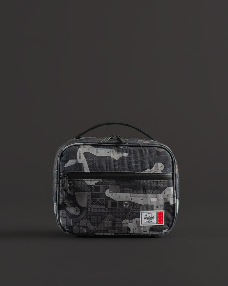 Herschel Supply Co. LEGO Pop Quiz Lunch Box in Abstract Bricks Black colorway featuring a pattern of black, grey, and white building bricks.