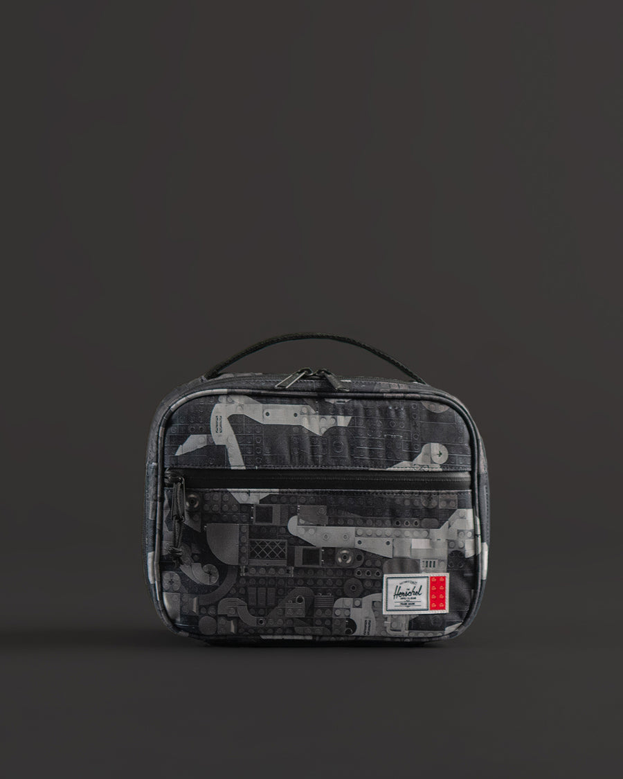 Herschel Supply Co. LEGO Pop Quiz Lunch Box in Abstract Bricks Black colorway featuring a pattern of black, grey, and white building bricks.