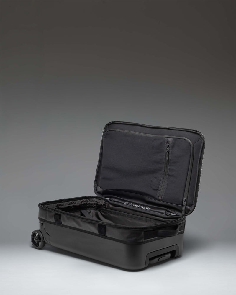 Herschel Supply Co. All Season Hybrid Roller Bag Large Carry On in black, showing the back of the luggage with wheels and handle.