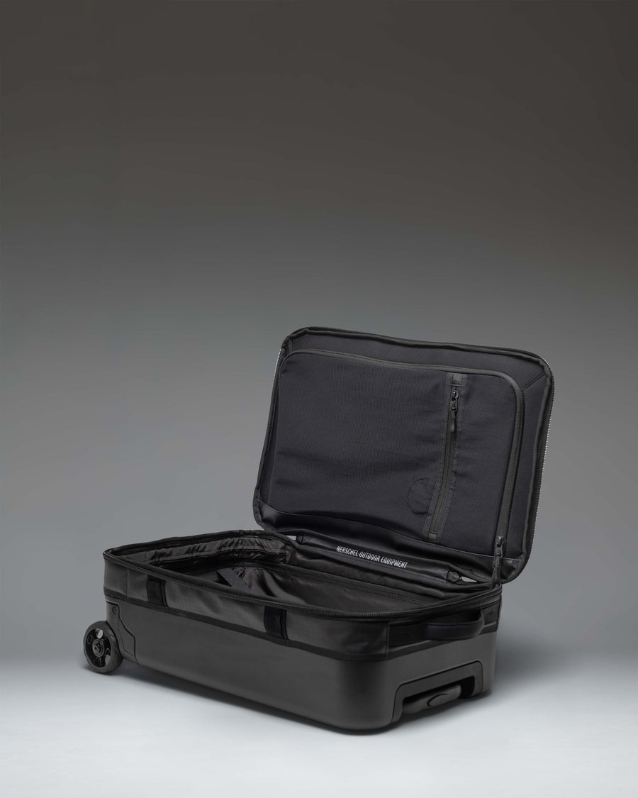 Herschel Supply Co. All Season Hybrid Roller Bag Large Carry On in black, showing the back of the luggage with wheels and handle.