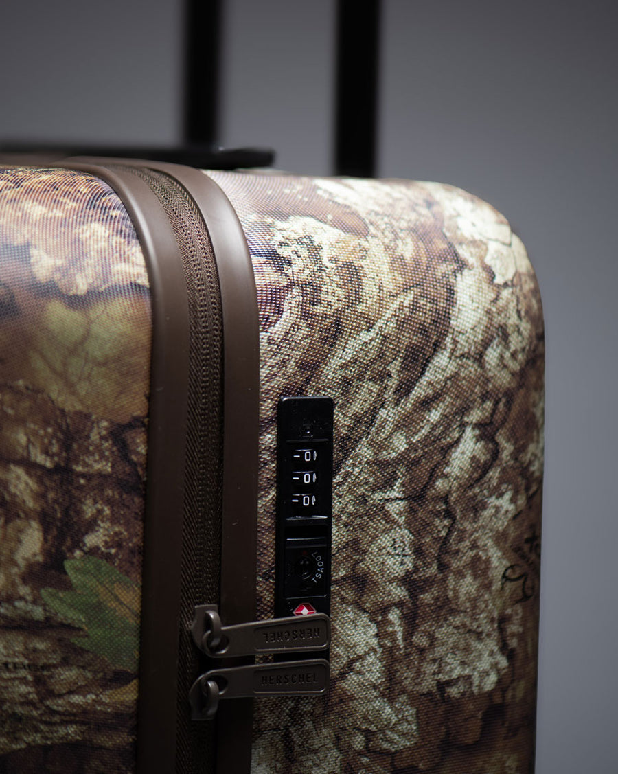 Realtree Herschel Heritage Large Luggage in Realtree APX Camo pattern hard shell suitcase.