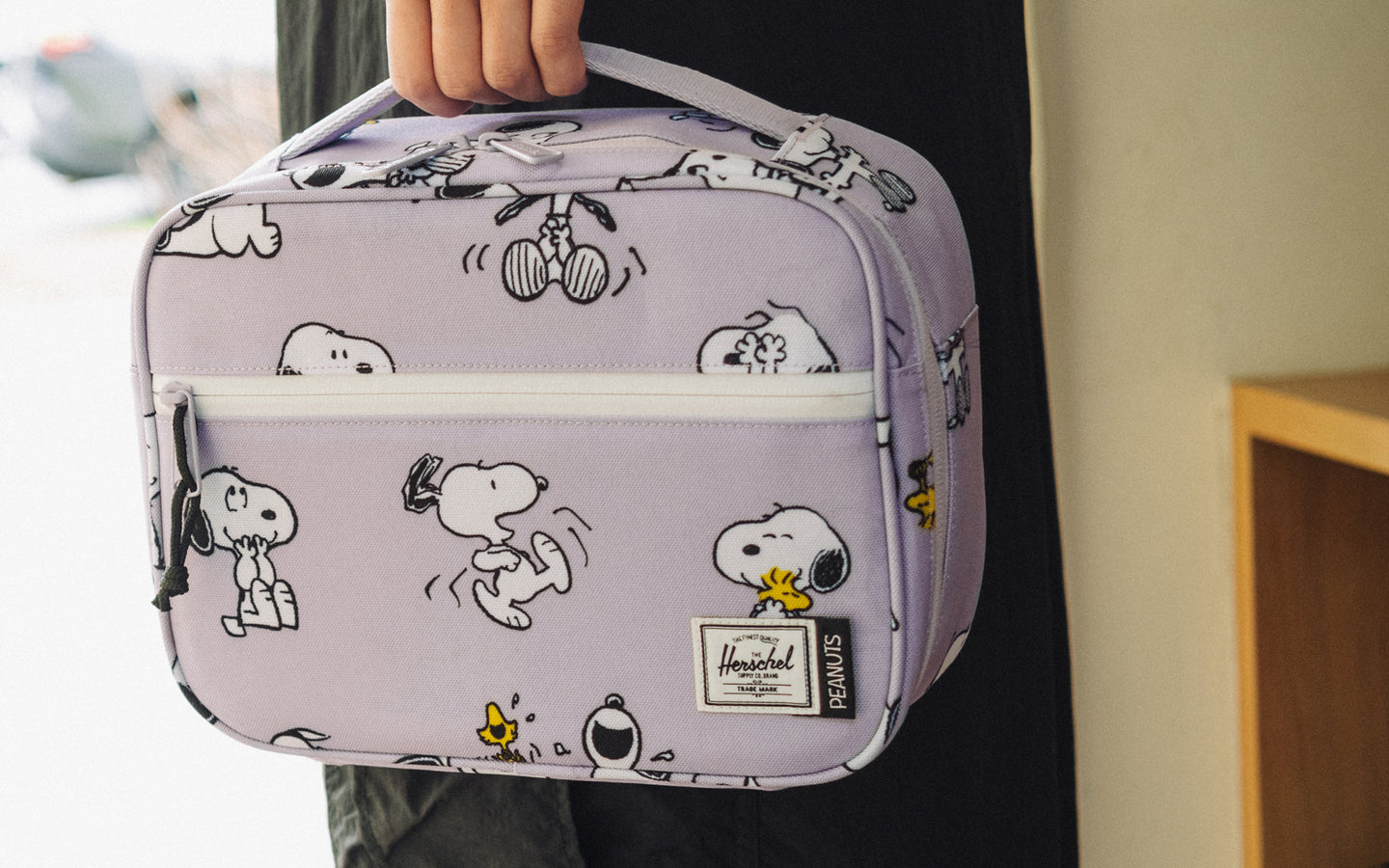 Herschel Supply Co. Peanuts Pop Quiz Lunch Box in Snoopy and Woodstock Pastel Lilac featuring a colorful graphic on a purple background.